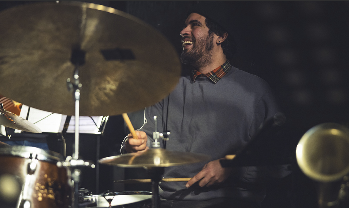 Matheus Jardim smiling while playing the drums